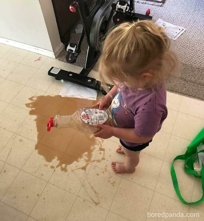 A toddler pouring syrup on the kitchen floor, highlighting questionable decisions in parenting.