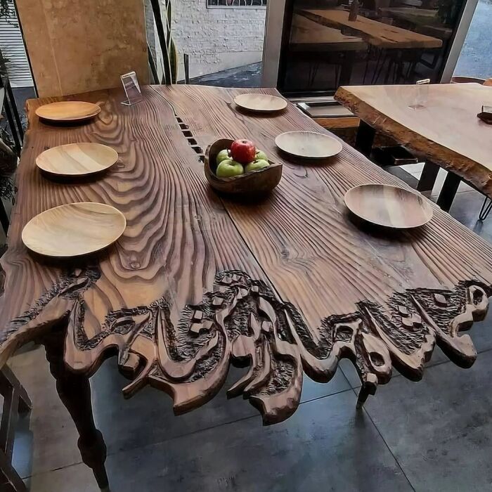 A hand-carved wooden dining table showcasing detailed wooden creations on the edges