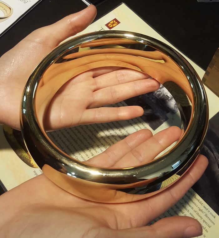 An oversized gold ring held in two hands, demonstrating detailed movie props.