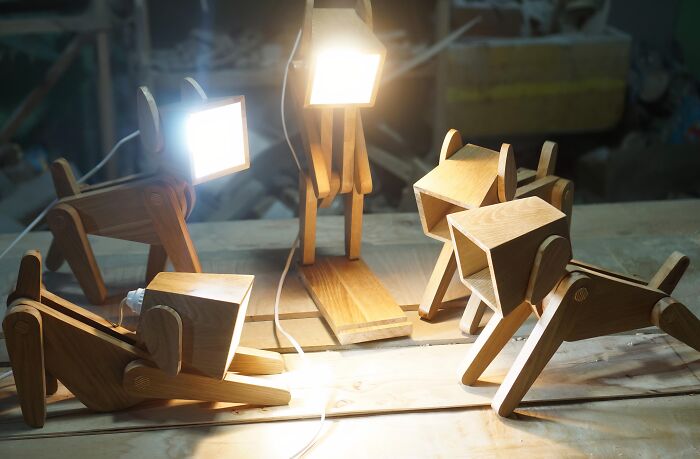 Clever wooden creations showing dog-shaped wooden desk lamps lit up on a workbench