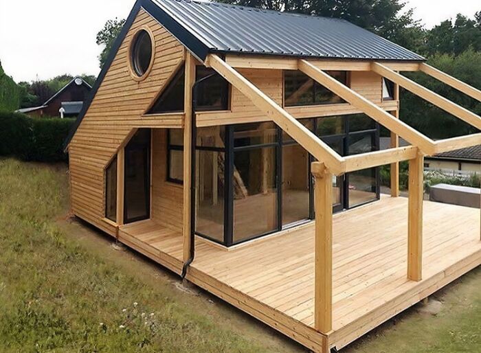 A modern cabin design showing clever wooden creations with large glass windows and an open deck