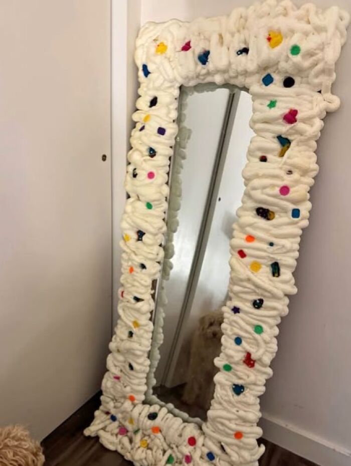 An odd craft project showing a full-length mirror surrounded by a messy foam frame.