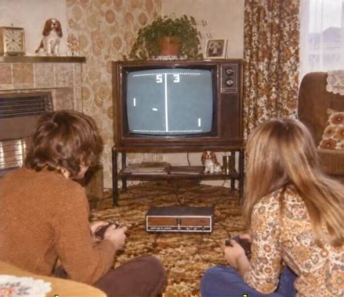 Two kids playing vintage Pong video game on 1970s home television
