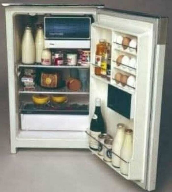 Vintage 1970s refrigerator stocked with bottles and jars inside an old kitchen appliance