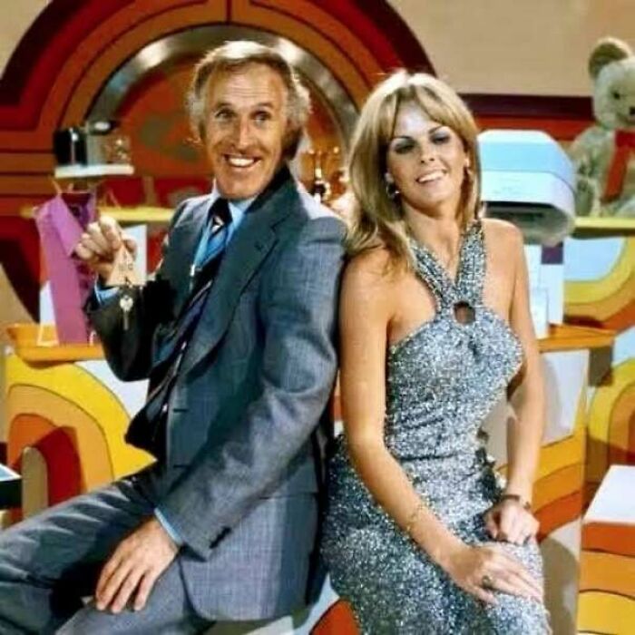 Vintage 1970s TV show hosts in colorful set and retro attire