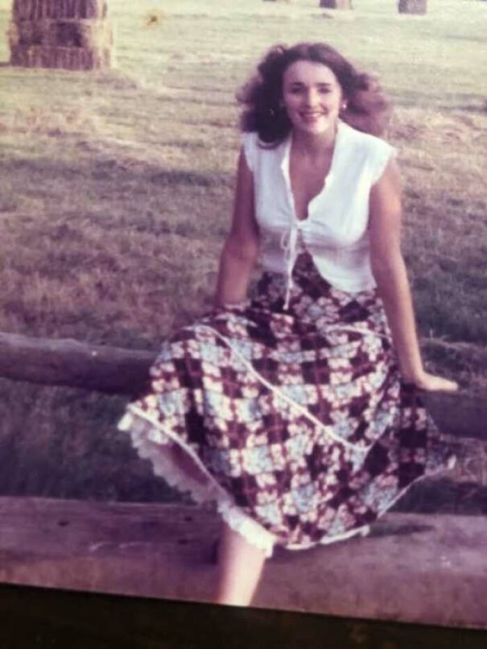 1970s outdoor portrait of woman sitting on fence wearing a floral maxi skirt