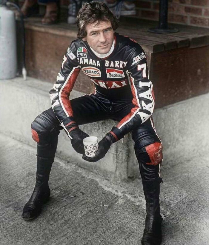Retro 1970s man in Yamaha leather racing suit sitting outdoors