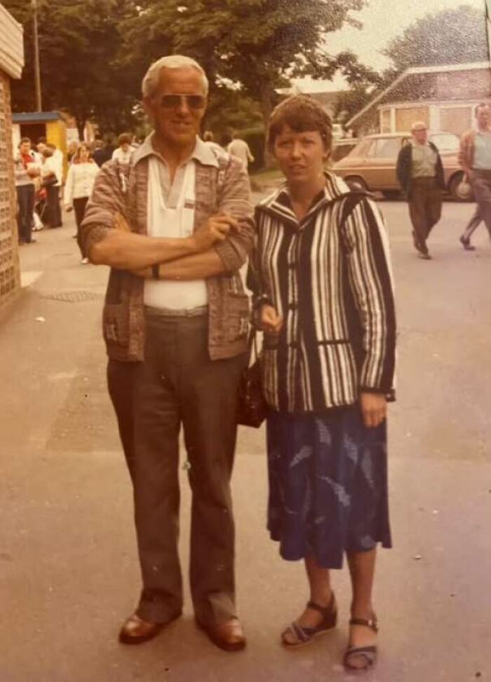 Couple in vintage 70s clothing posing on a sidewalk in old photo