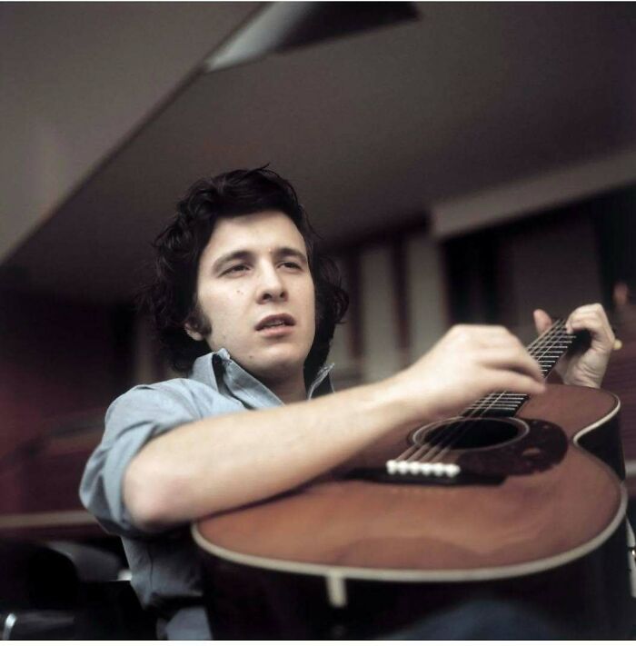 Young man playing acoustic guitar in 70s style photo