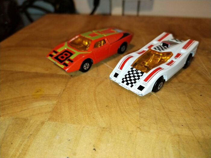 Two vintage 70s toy race cars on wooden surface closeup