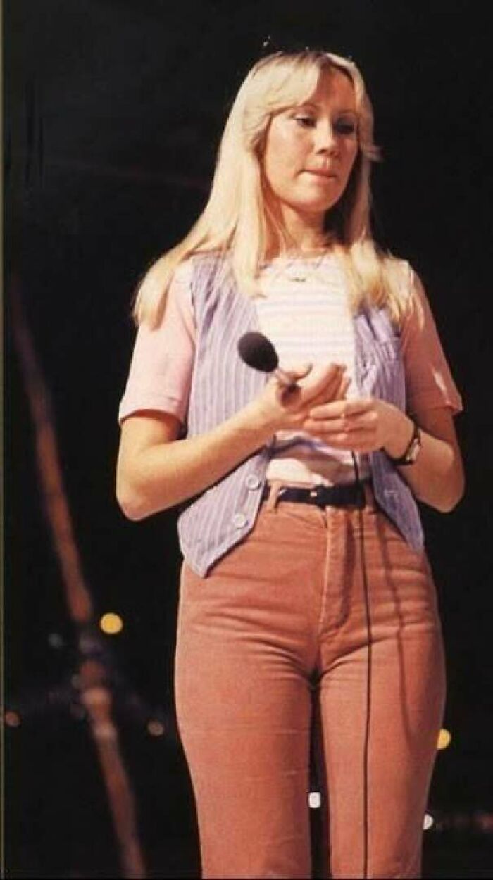 1970s photo of woman in vintage clothes holding microphone on stage