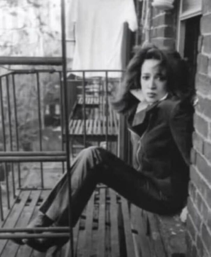 1970s vintage photo of woman sitting on metal fire escape outside brick building
