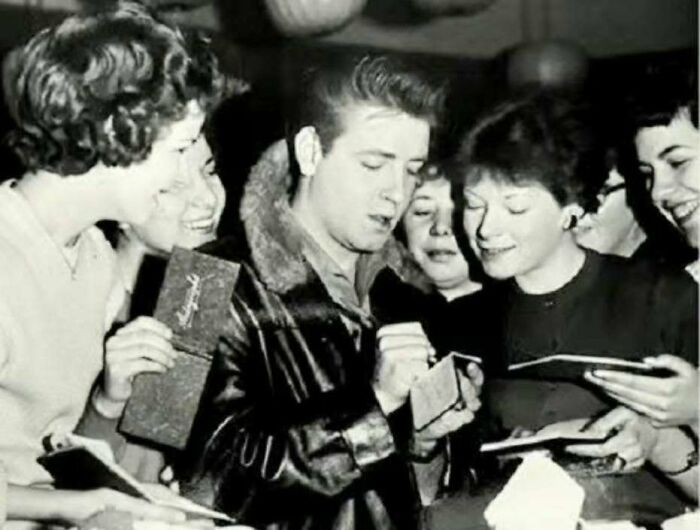 Black and white 1970s photo of Elvis Presley signing autographs for fans