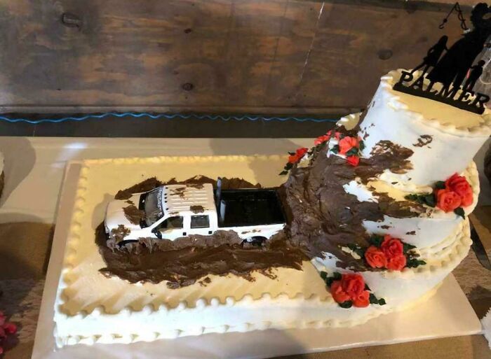 Questionable wedding cake designed with a white toy pickup truck driving through chocolate mud.
