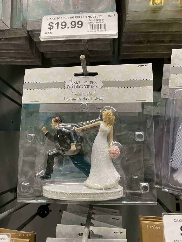 A retail package of a humorous wedding cake topper showing a bride pulling a running groom.