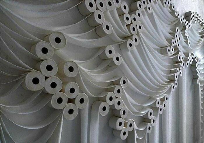 A questionable wedding arch decorated entirely with rolls of toilet paper draped like curtains.