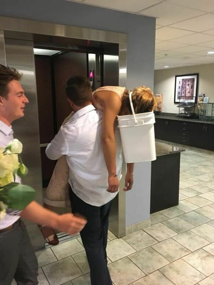 A man carrying a woman with a bucket on her head down a hallway, showing questionable wedding moments.