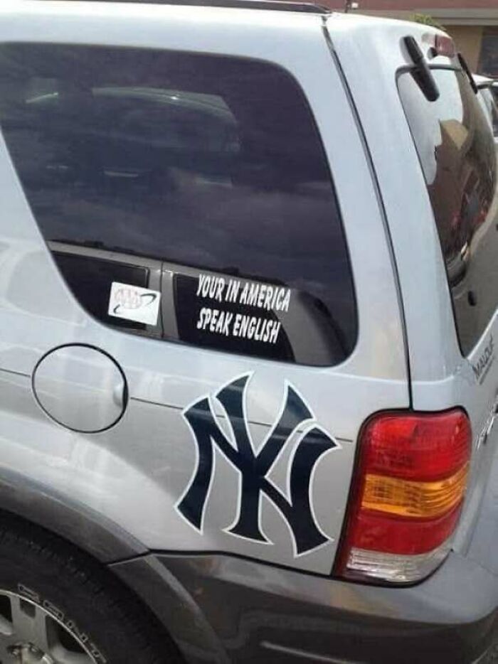 A car bumper sticker with the grammatical error your in America speak English.