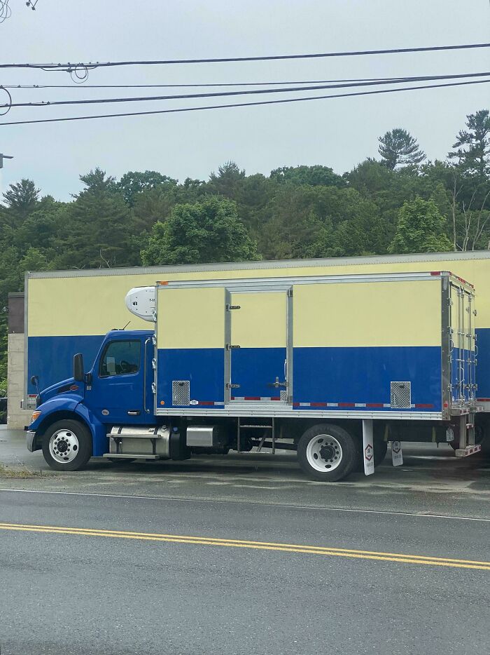 A blue and yellow truck matching the background building wall perfectly in accidental camouflage