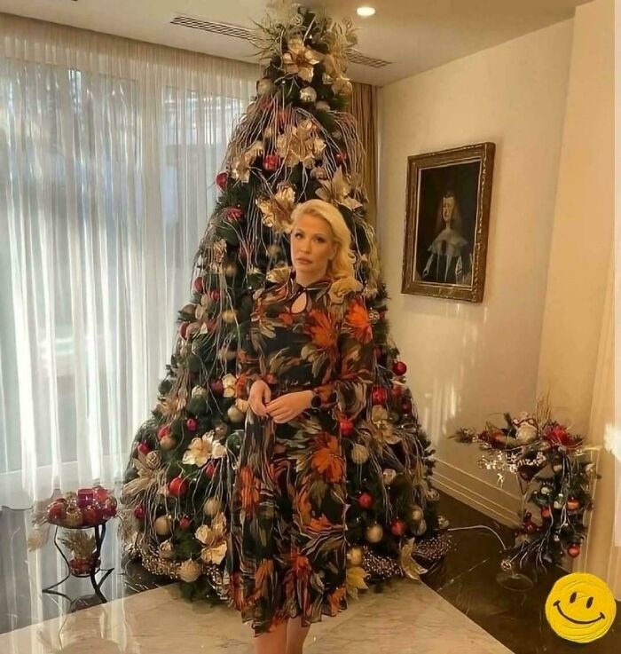 A woman wearing a floral dress matching a decorated Christmas tree in accidental camouflage