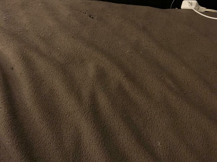 A brown blanket showing ripples like a dessert as an example of accidental camouflage