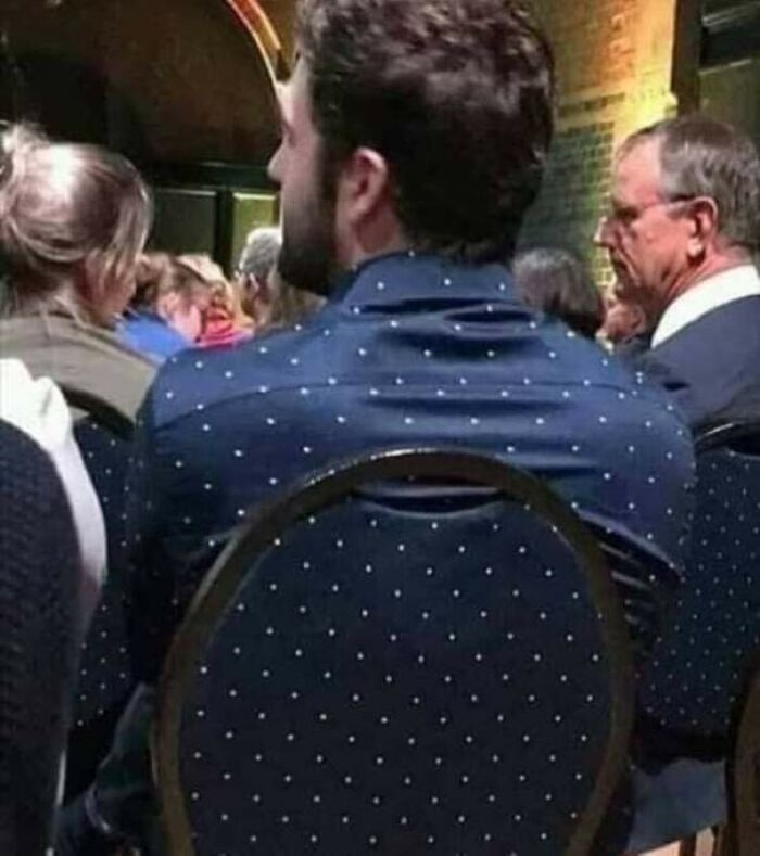 Accidental camouflage of a man in a polka dot shirt blending with a matching chair