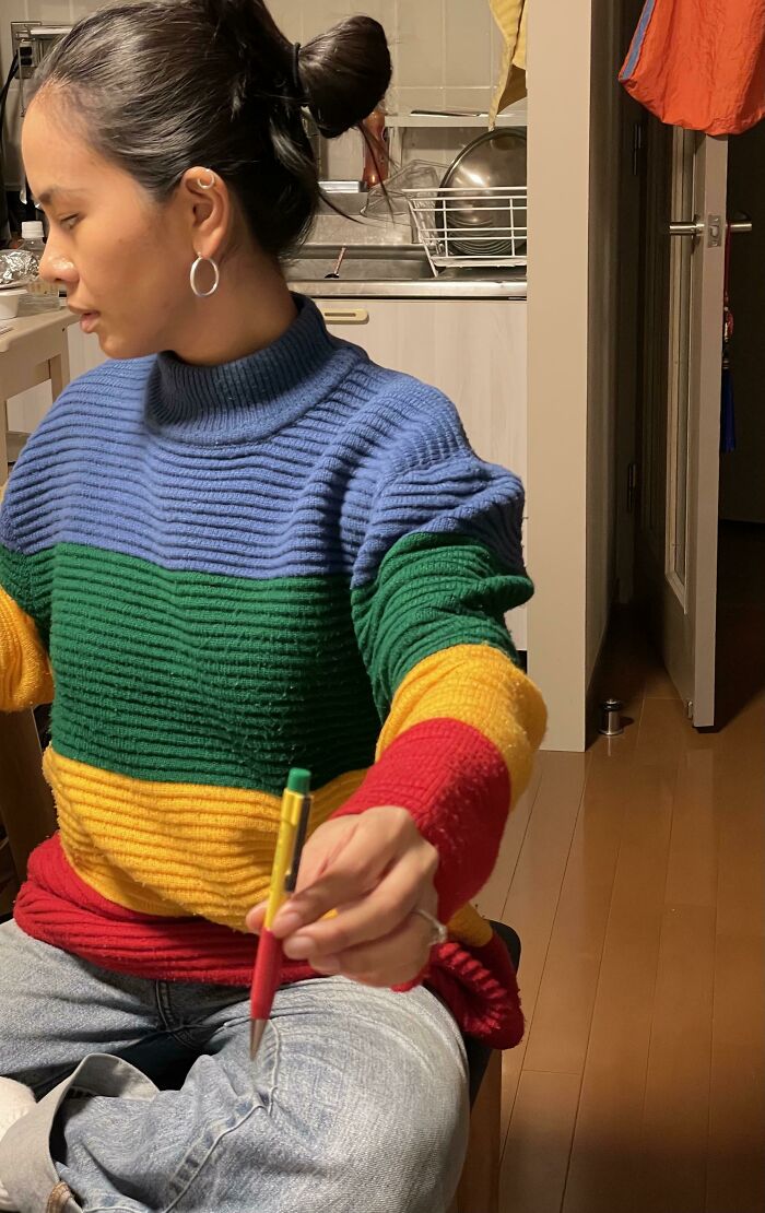 Woman wearing striped sweater matching her multi-colored pen in accidental camouflage