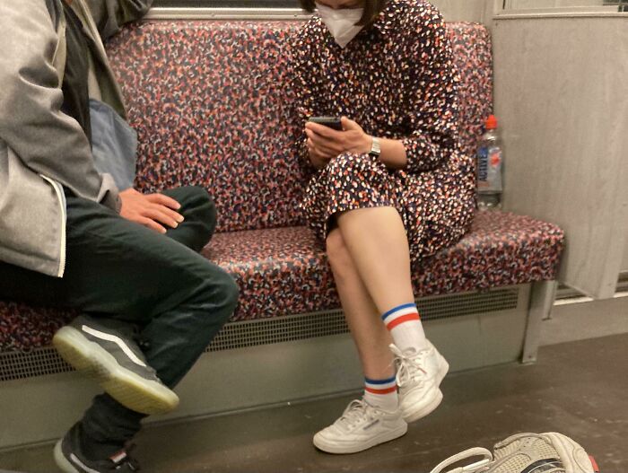 Woman in patterned dress matching train seat pattern in accidental camouflage