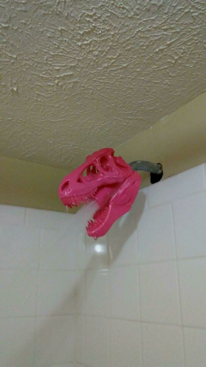 A pink T-Rex skull shower head attachment made using a 3D printer