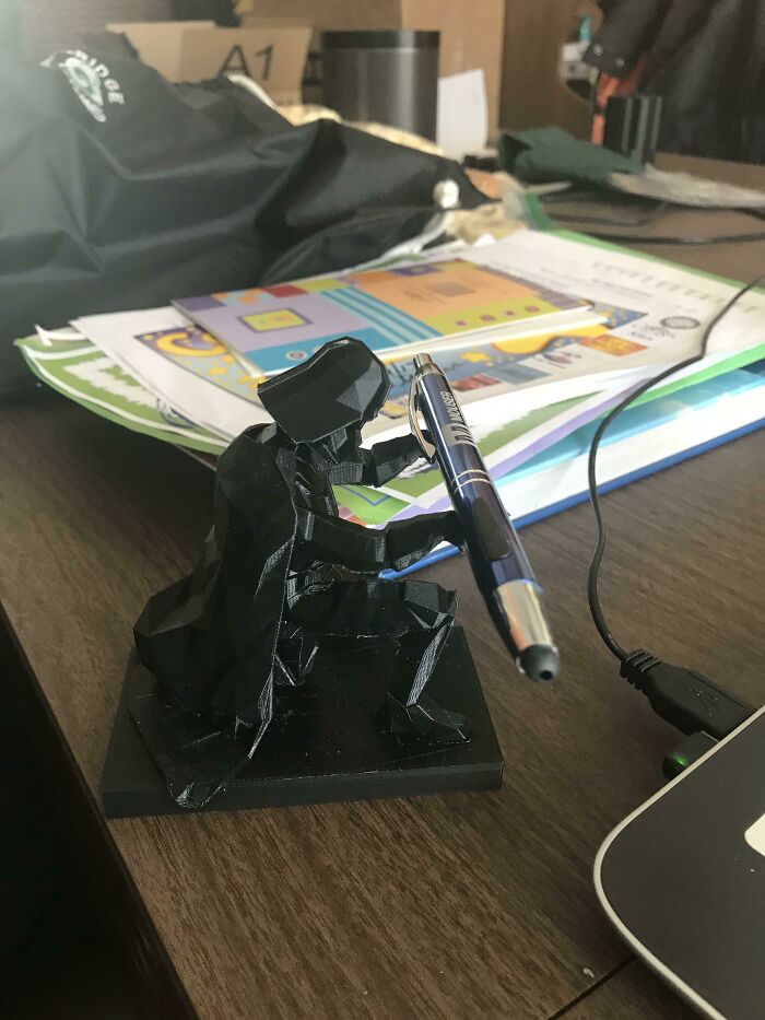 A black Darth Vader desk organizer holding a pen, showcasing 3D printer creativity.