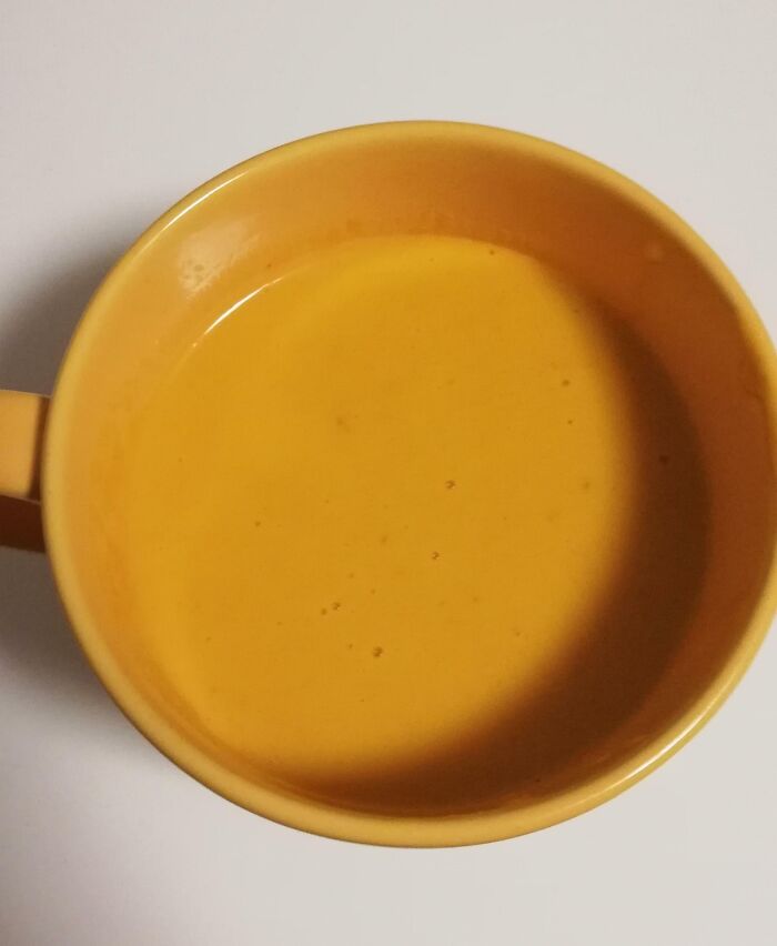 A cup of soup that matches the color of the mug perfectly as accidental camouflage