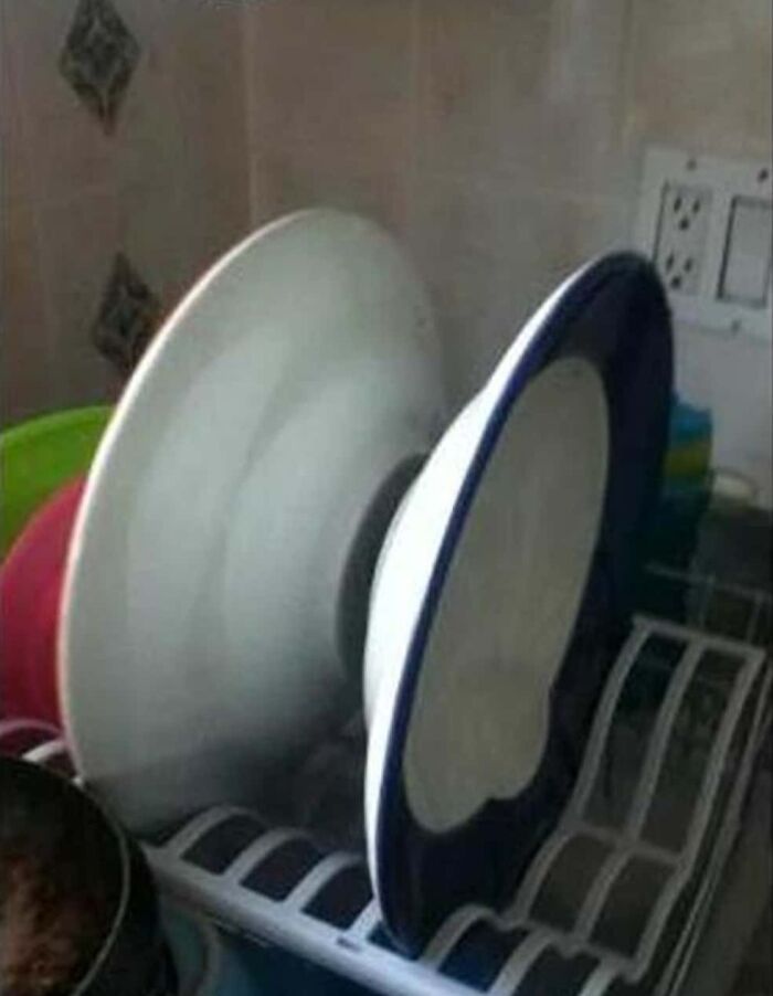A white dish drying rack with two plates stacked in an unsatisfying back-to-back way