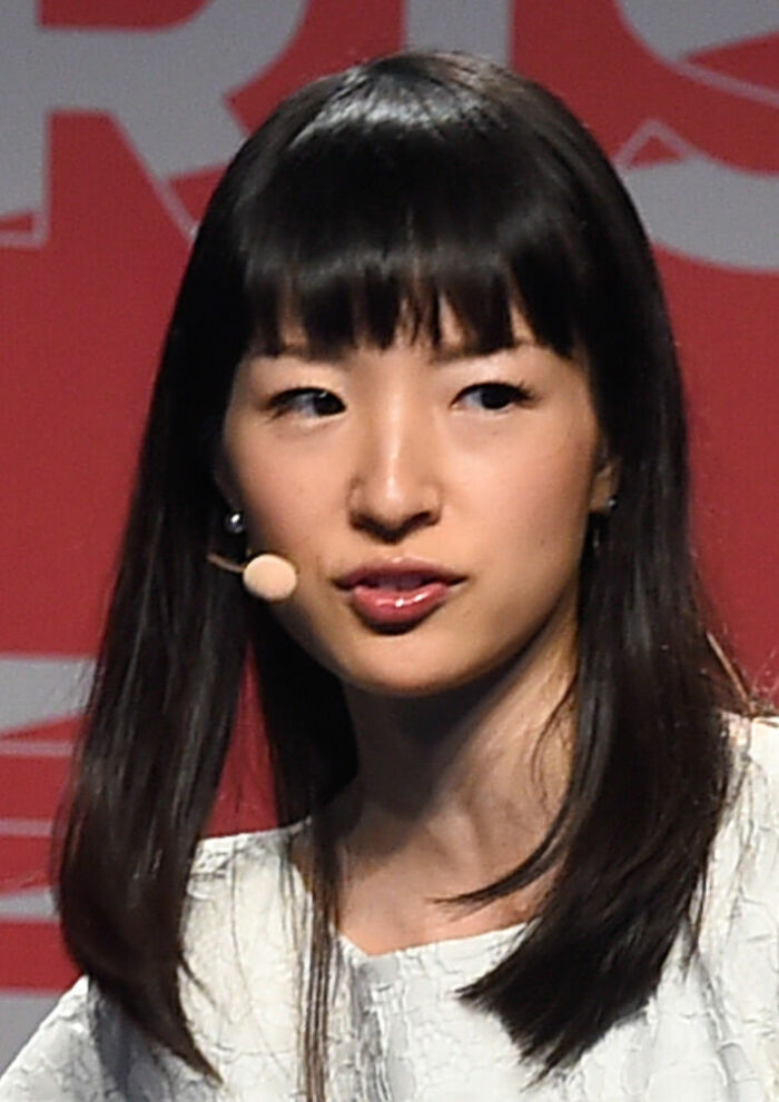 A close-up of Marie Kondo speaking on stage with a headset microphone