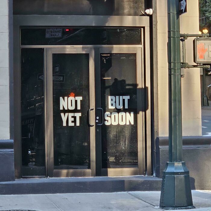 Storefront glass doors with confusing text alignment, showing badly designed signs.