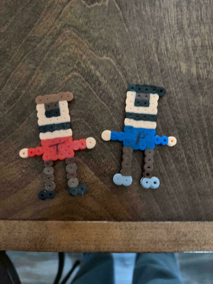 Two colorful plastic bead figures on a wooden surface, part of wholesome pics of dads embracing fatherhood creativity.