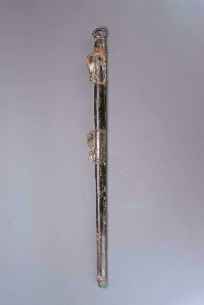 Long ancient metal artifact with corroded patina and detailed fittings