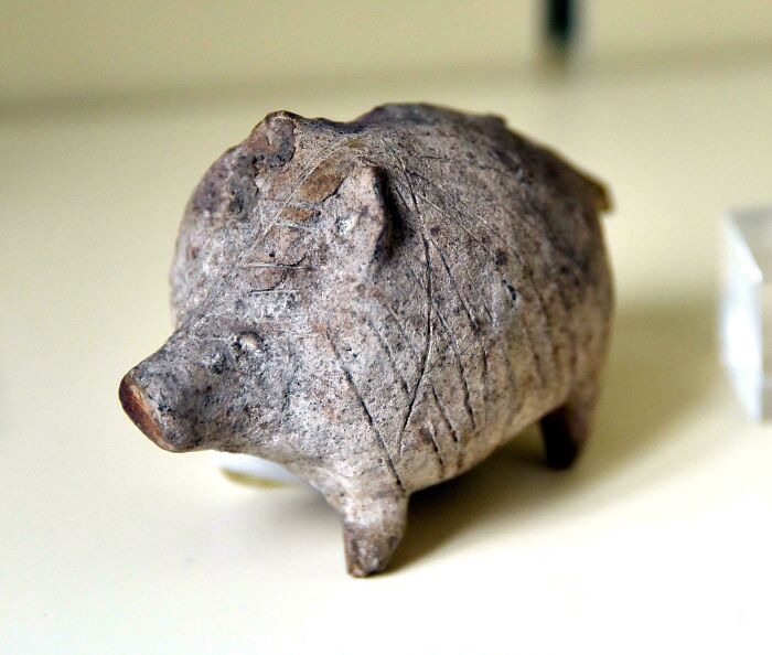 Ancient carved pig-shaped artifact with engraved patterns