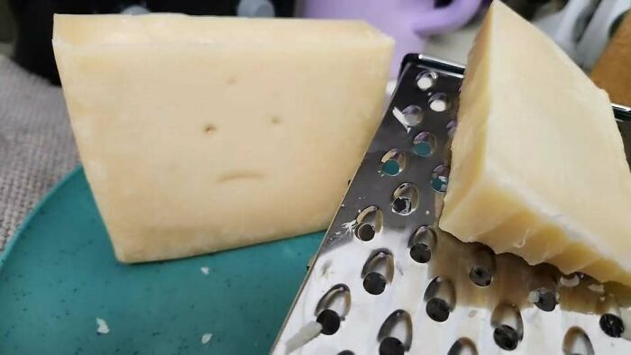 Block of cheese with holes that look like eyes and a mouth