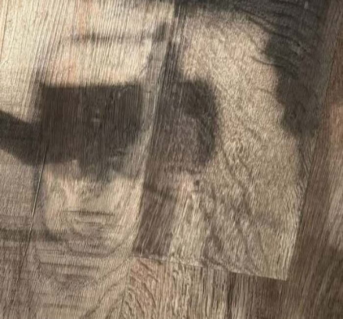 Shadow on wooden floor creating illusion of a staring face