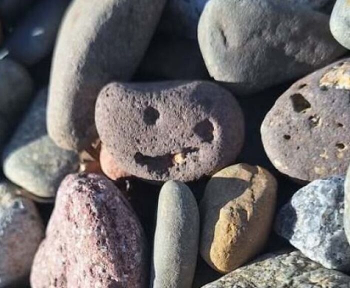 Rock with natural holes resembling a smiling face among other stones