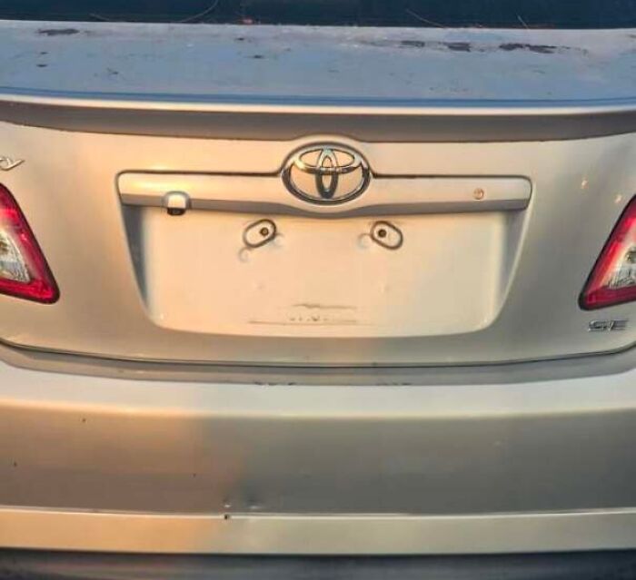 Car rear with dents and bolts resembling eyes and a surprised face.