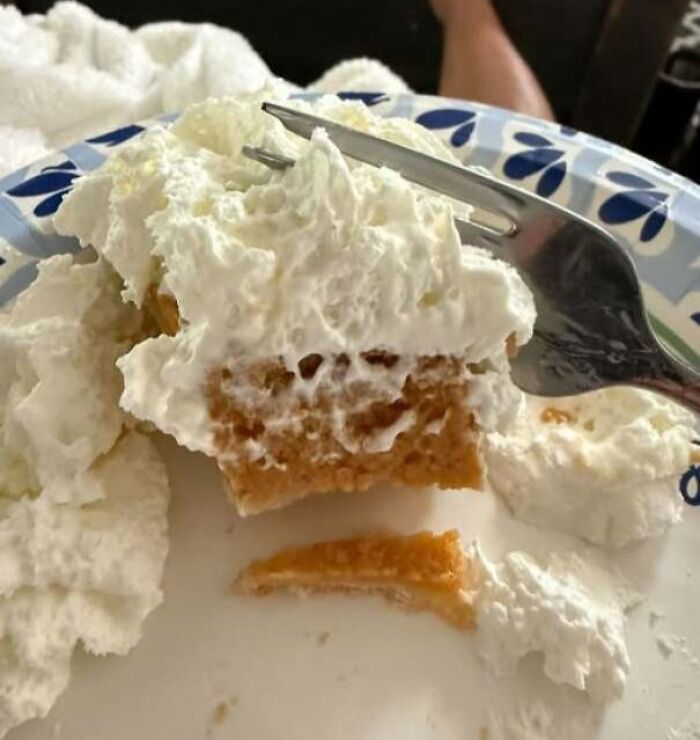 Dessert with whipped cream and fork creating a face-like appearance.