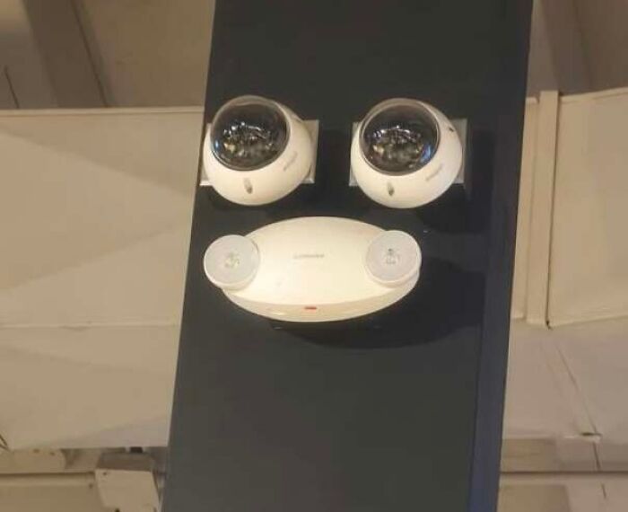 Two security cameras and a white device resembling a face staring