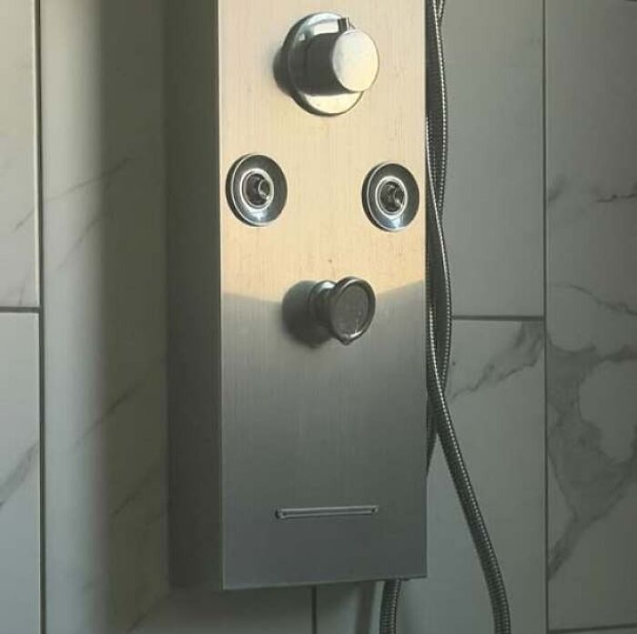 Shower panel with knobs and nozzles resembling a staring face