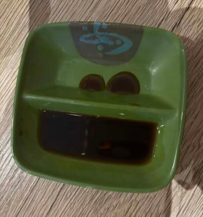 Green dish with soy sauce patterns resembling eyes and mouth