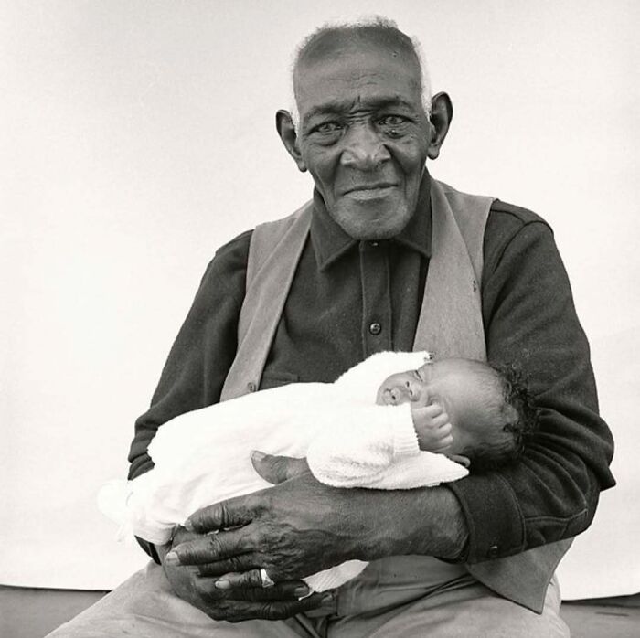 Black and white photo of elderly man holding baby in his arms