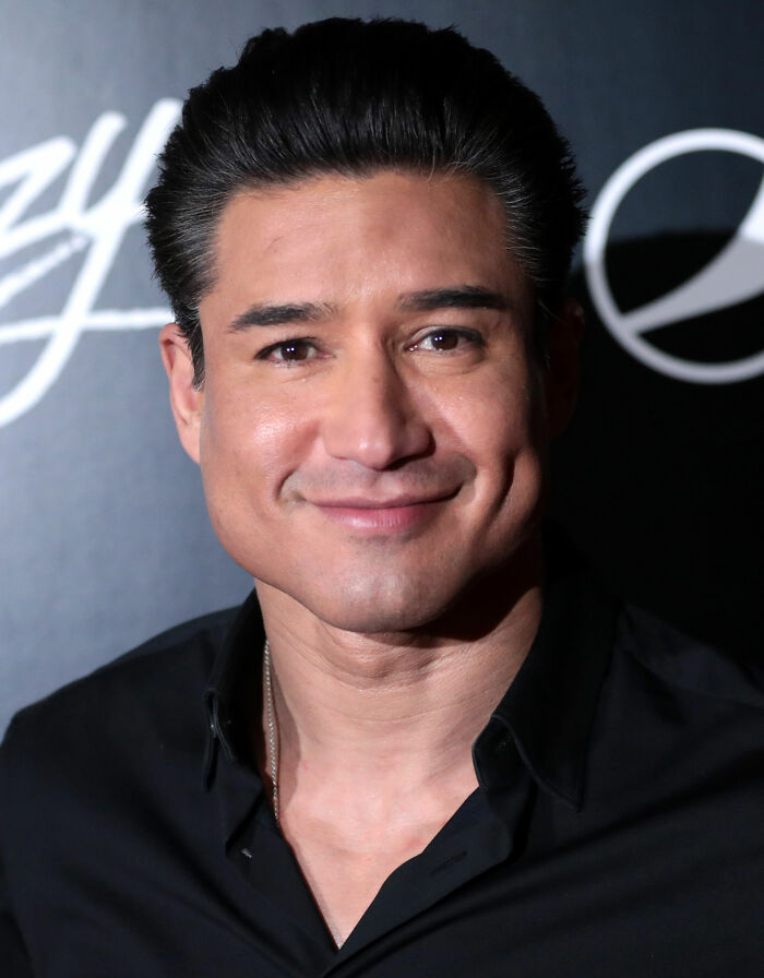 Close-up portrait of Mario Lopez smiling in a black shirt at an event.