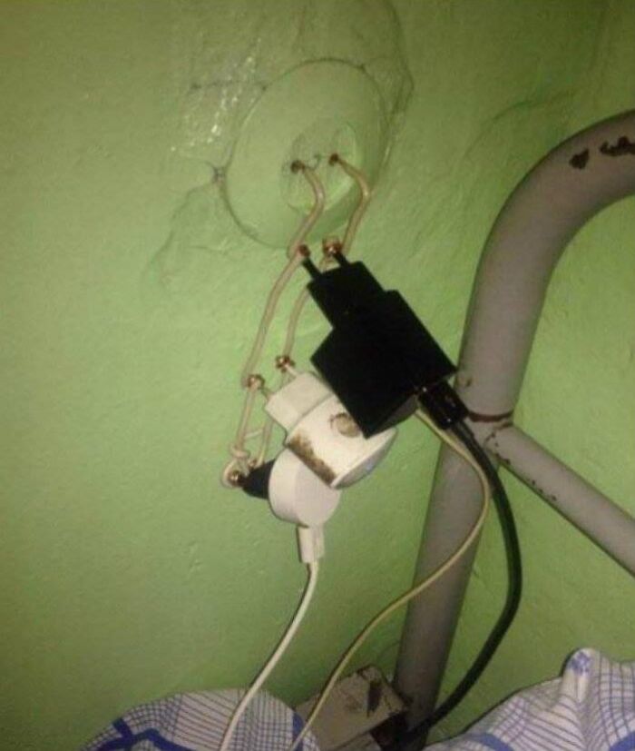 Dumb redneck fixes using exposed wires to connect multiple power plugs to a green wall outlet.