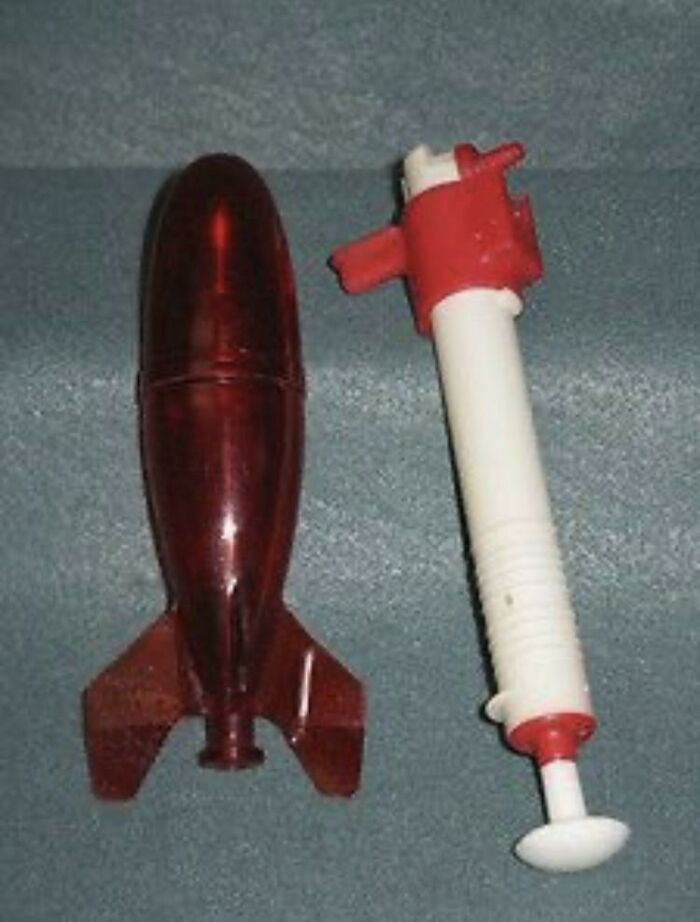 Retro red and white toy rocket and launcher on gray background
