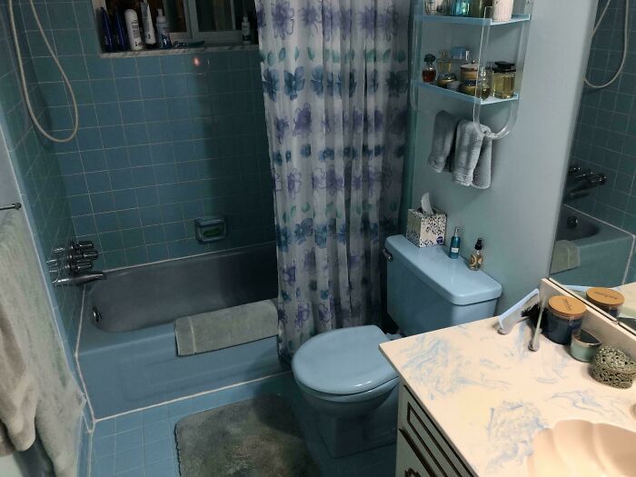 Vintage blue bathroom with floral shower curtain and matching tiles and fixtures